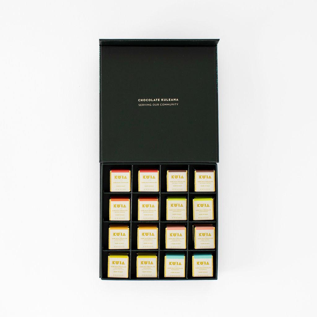 Open Maui Kuʻia Estate gift box with individually wrapped chocolate squares arranged in a black tray.
