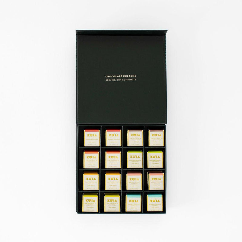 Open Maui Kuʻia Estate gift box with individually wrapped chocolate squares arranged in a black tray.
