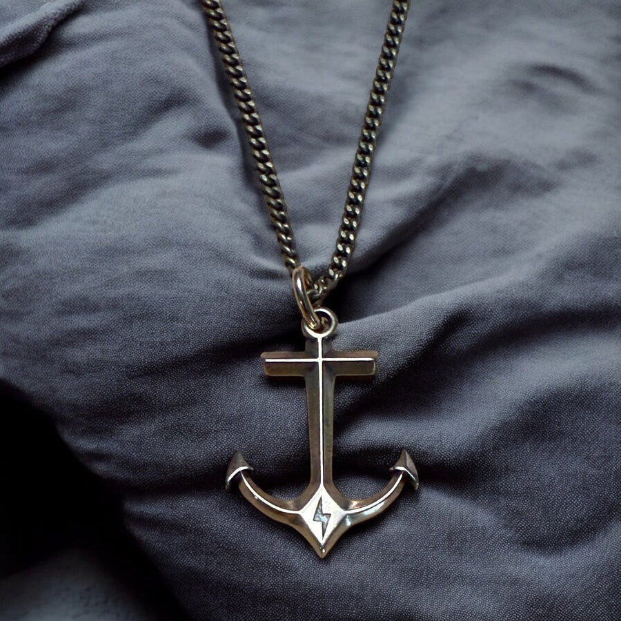 Anchor pendant resting on dark fabric