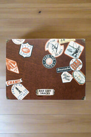 Vintage case of Bar Cart Snacks featuring assorted nostalgic stickers on a wooden background