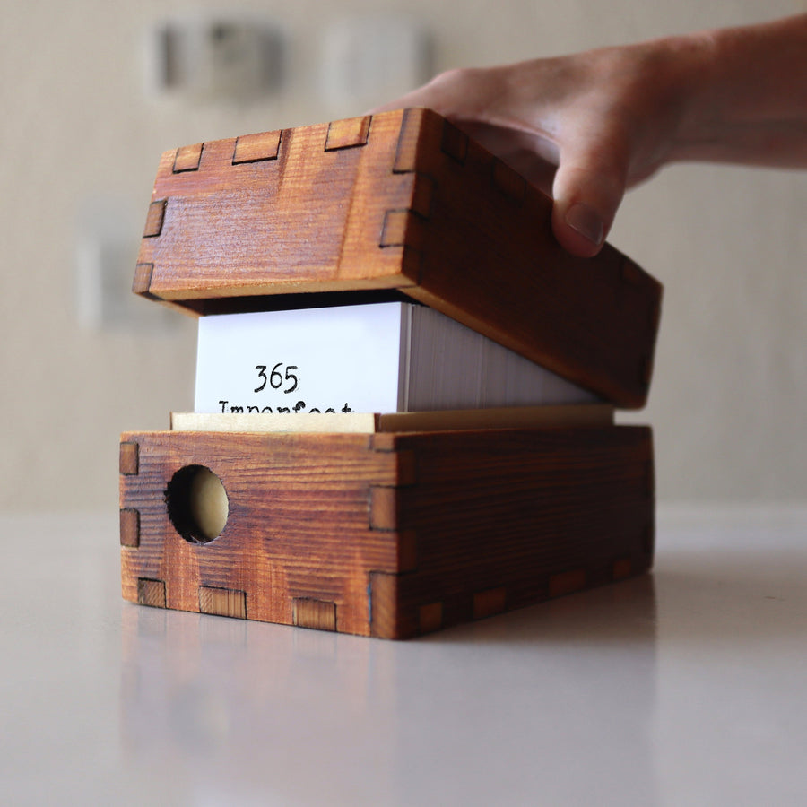 Optional wooden storage box holding a 365 Imperfect Cards set.