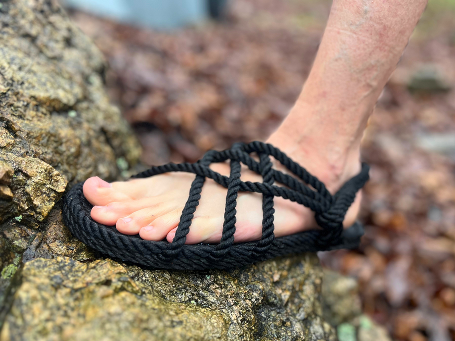 Black Utopian rope sandal worn outdoors on rocky ground