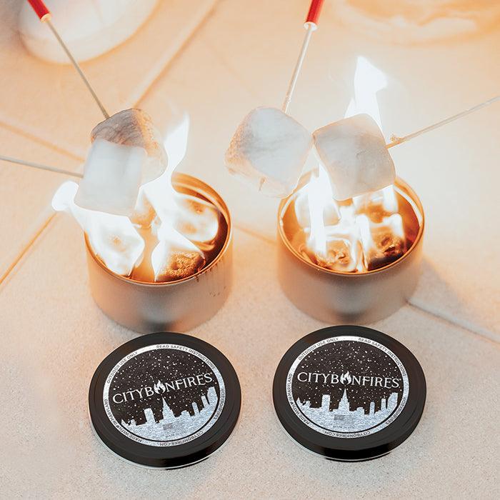 Two lit portable bonfires with marshmallows roasting above them