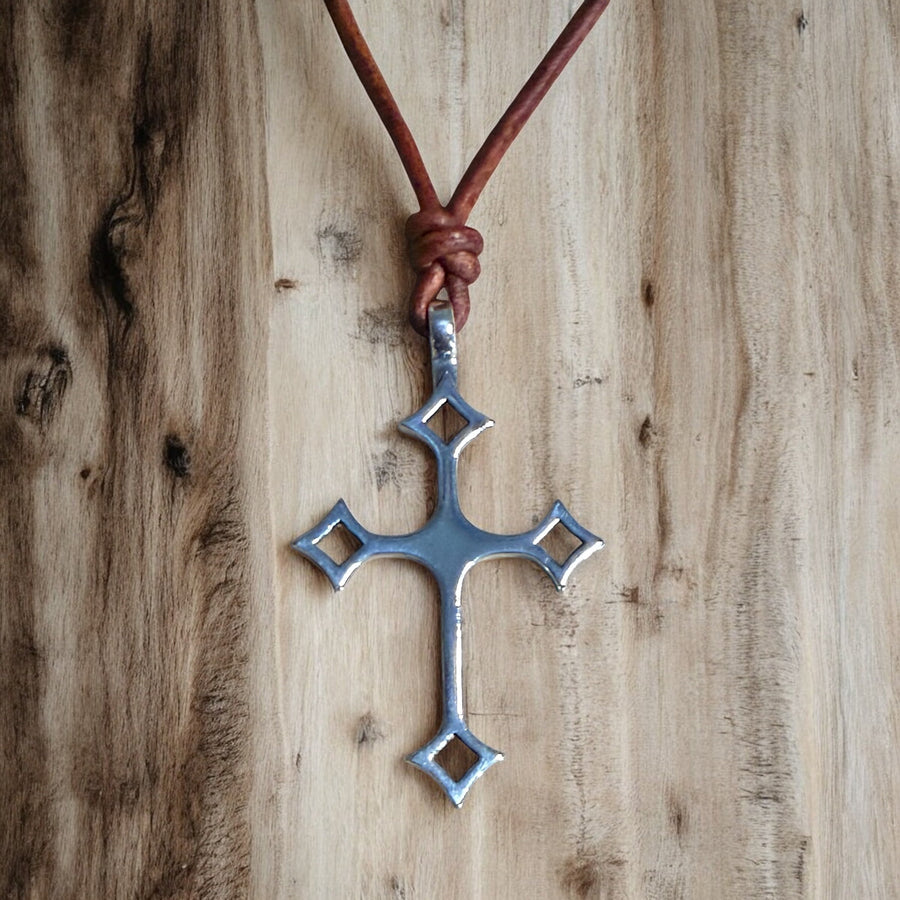 Gothic cross on brown leather cord against wood