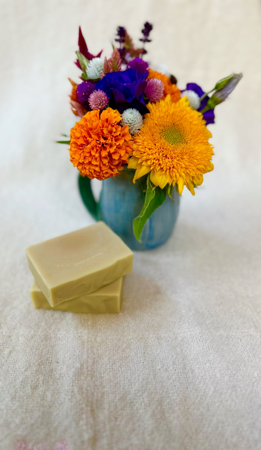 Stacked unscented soap bars beside a colorful flower arrangement