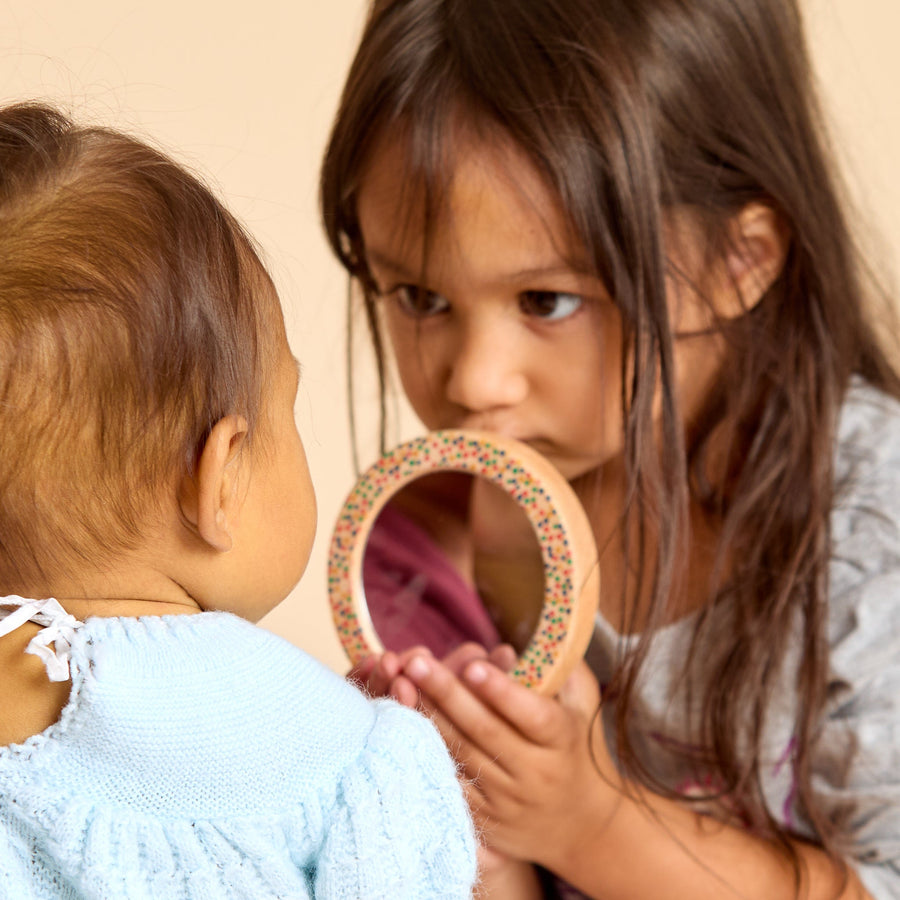 Children looking into round discovery mirrors during shared play
