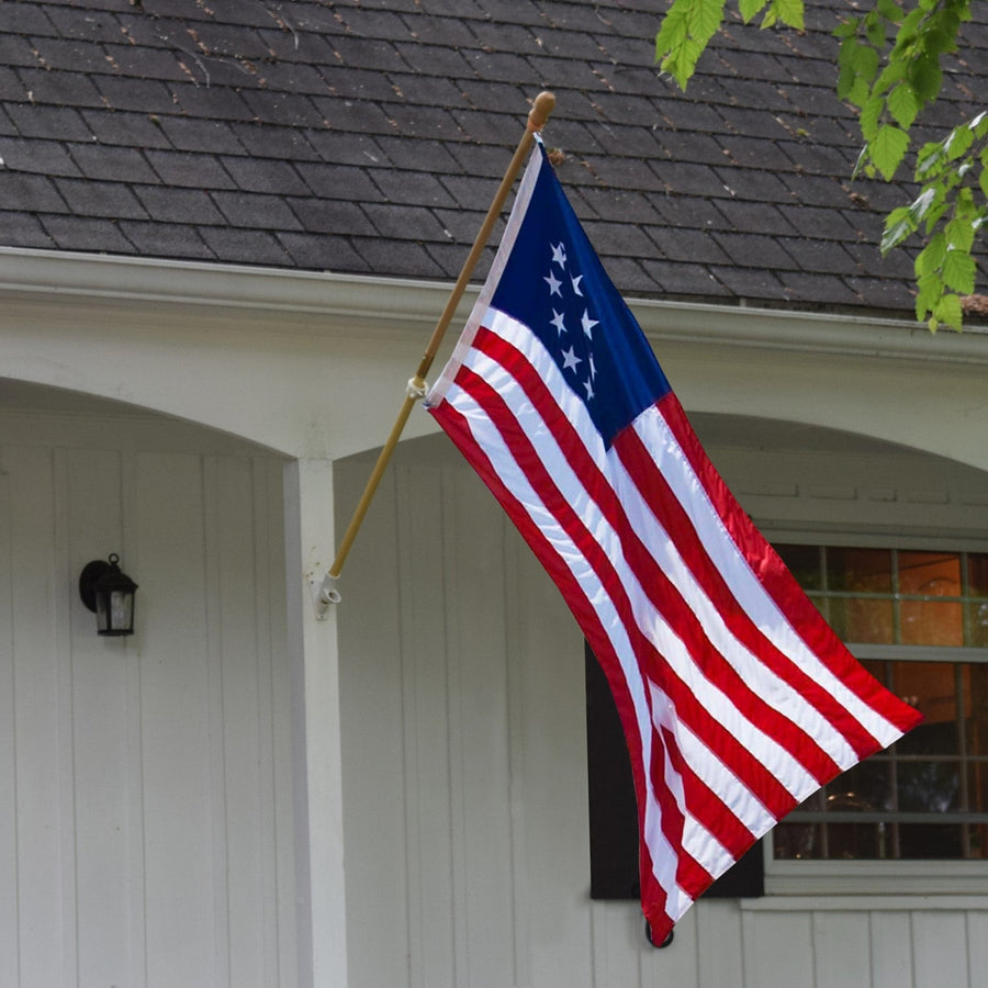 Betsy Ross flag with 13-star circle flying from a house-mounted flagpole