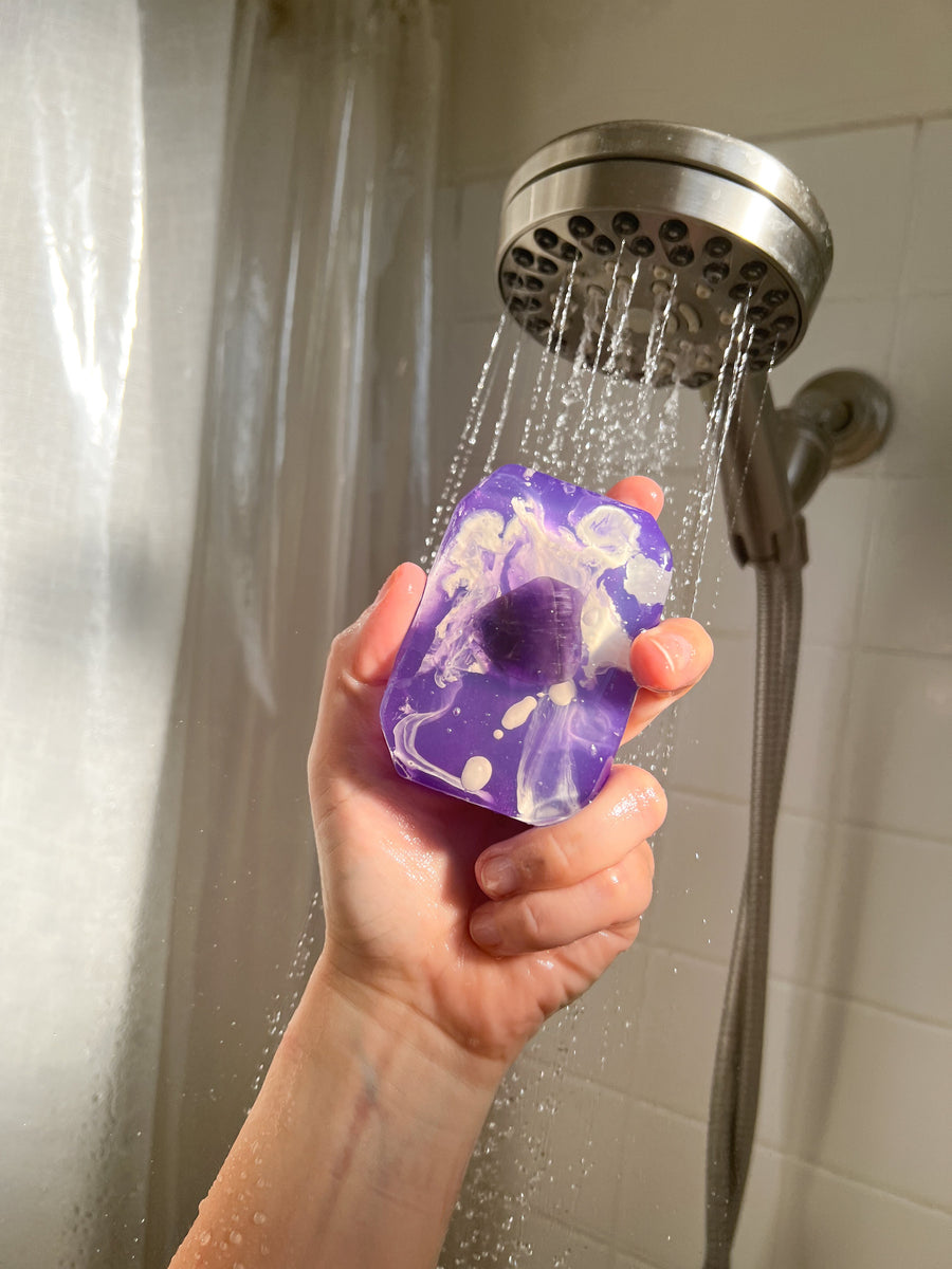 Peace Bridge amethyst soap held beneath a showerhead