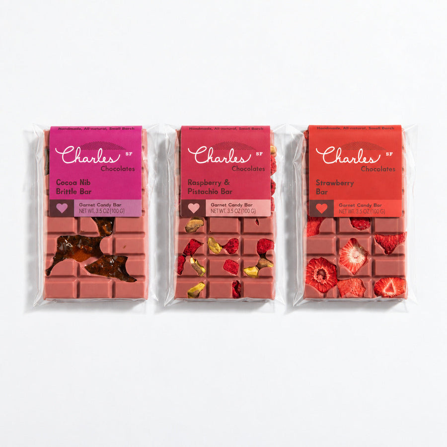 Three wrapped ruby chocolate bars in strawberry, raspberry-pistachio, and cocoa-nib flavors