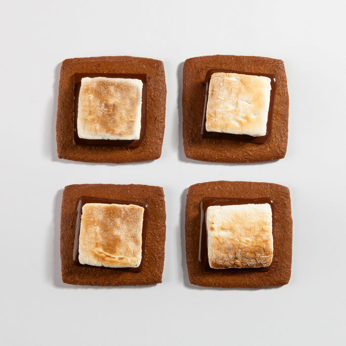 Four assembled chocolate and marshmallow smores on graham cracker squares