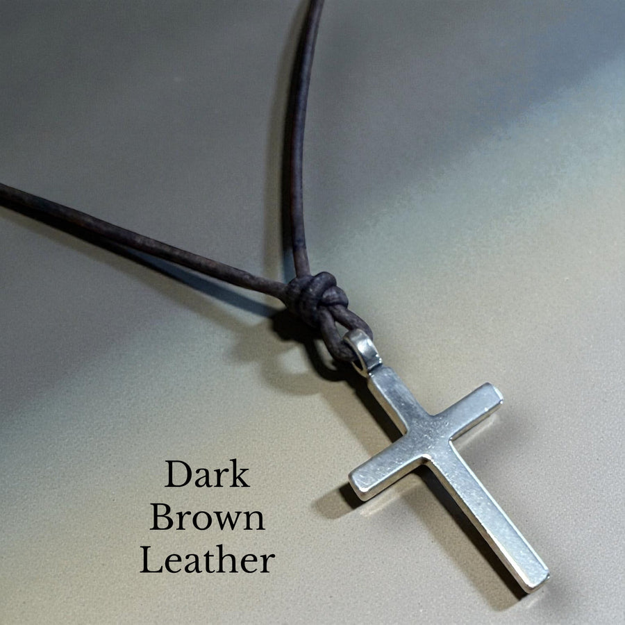 Classic cross and dark brown leather cord against gray