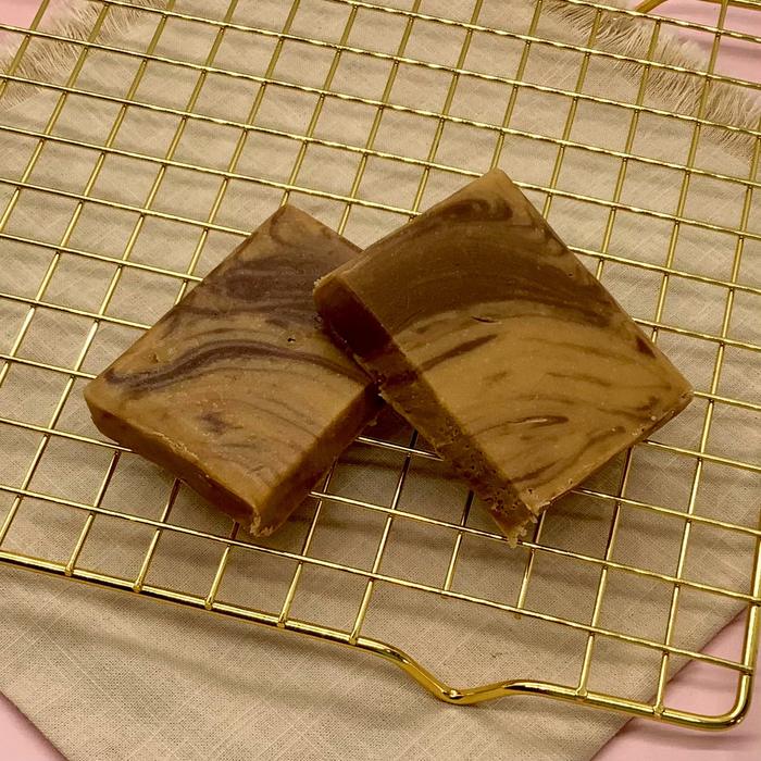Chocolate caramel fudge squares with golden and brown swirls on a gold wire rack.