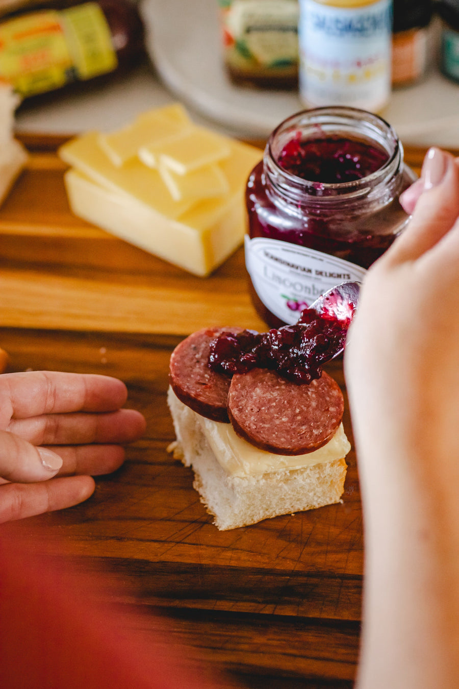 Lingonberry spread spooned onto sausage and cheese on a cracker; serving suggestion