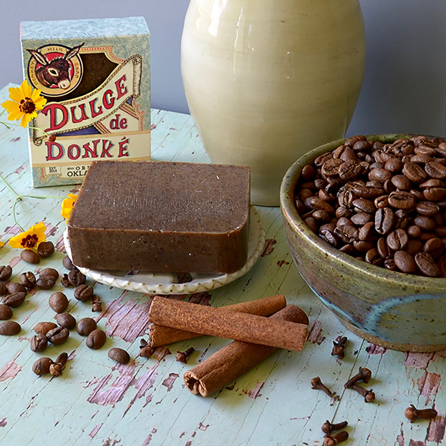 Spiced coffee soap beside coffee beans, cinnamon sticks, milk, and its box