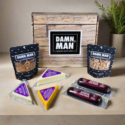 Snack box with 'Damn, Man' branding on a wooden surface with snacks displayed.