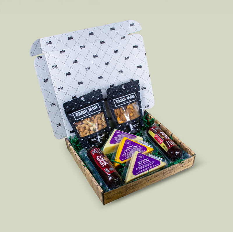 Gift box with snacks and cheeses on a light beige background