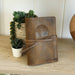 Closed desert sand brown leather journal resting on a wooden table.