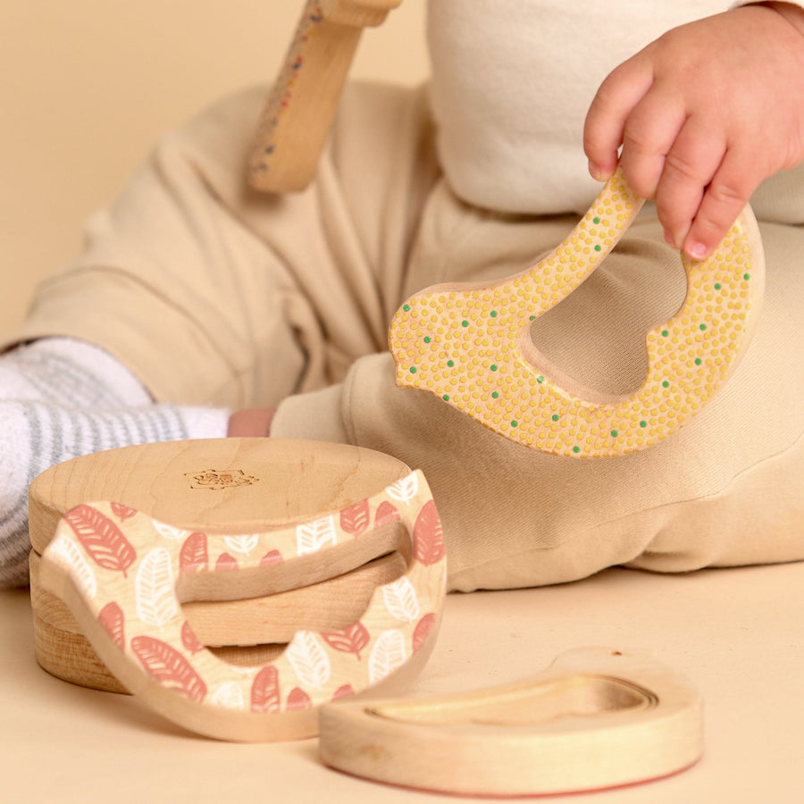 Child grasping and exploring a bird-shaped wooden rattle