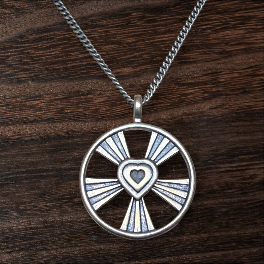 Shining Heart pendant with openwork rays against wood