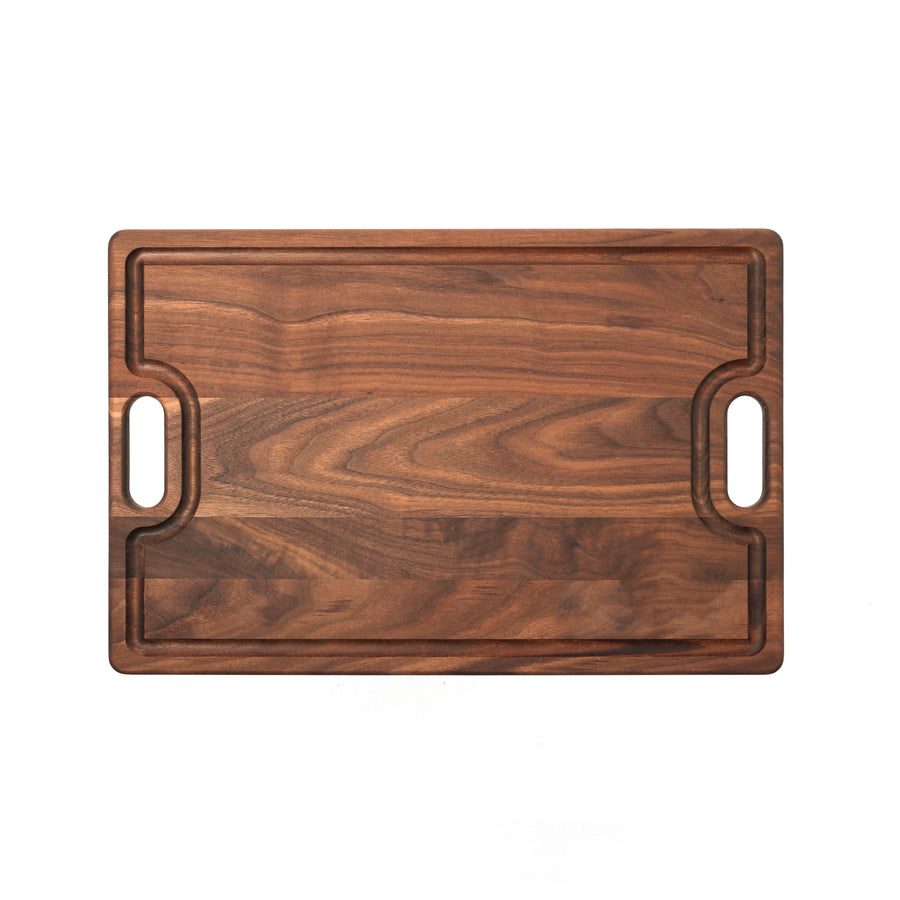 Overhead view of a walnut board with cutout handles and a shaped groove
