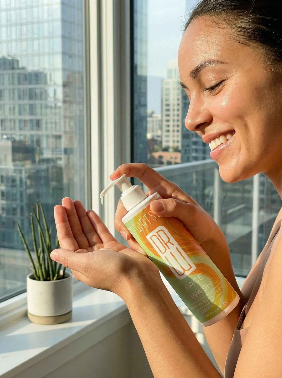Person dispensing Dr. Watson's face wash into a palm by a window
