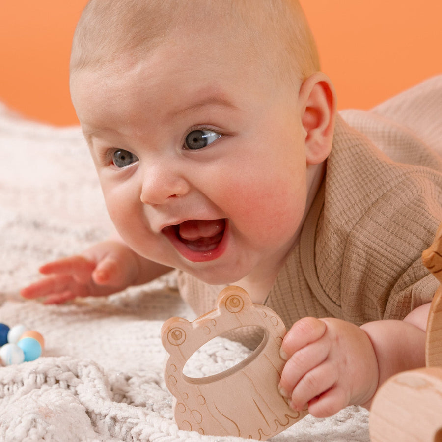Baby holding a wooden animal-shaped teether