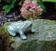 Stoneware frog figurine placed on a garden stone