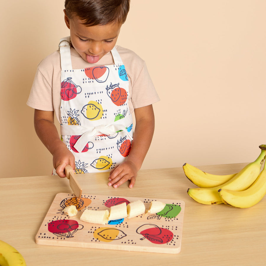 Child using a wooden knife and illustrated cutting board during food preparation
