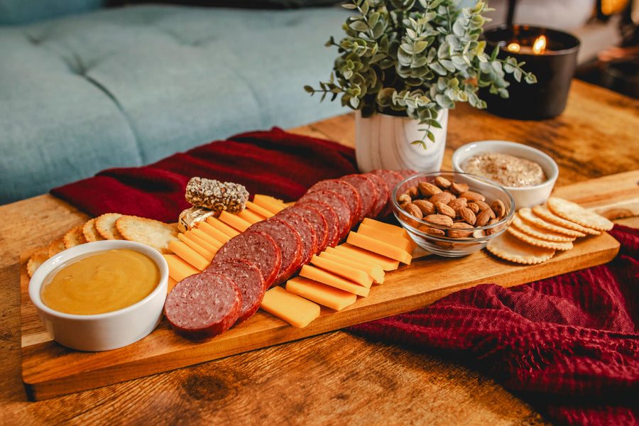 Sausage, sliced cheese, crackers and nuts arranged on a wooden board; serving suggestion