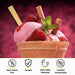 A waffle cone filled with strawberry ice cream topped with fresh raspberries, a sprig of mint, and a rolled wafer, with an unwrapped bamboo dessert spoon from Holy City Straw Co. inserted into the scoop. Below the cone are icons with text stating "100% Plastic Free", "Durable", "100% USDA Biobased", and "Certified Compostable". The background is a vivid red with a bokeh effect.