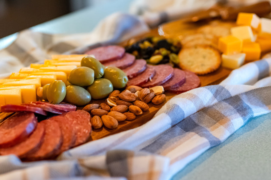 Sausage, cheese, crackers, olives and nuts on a board; serving suggestion
