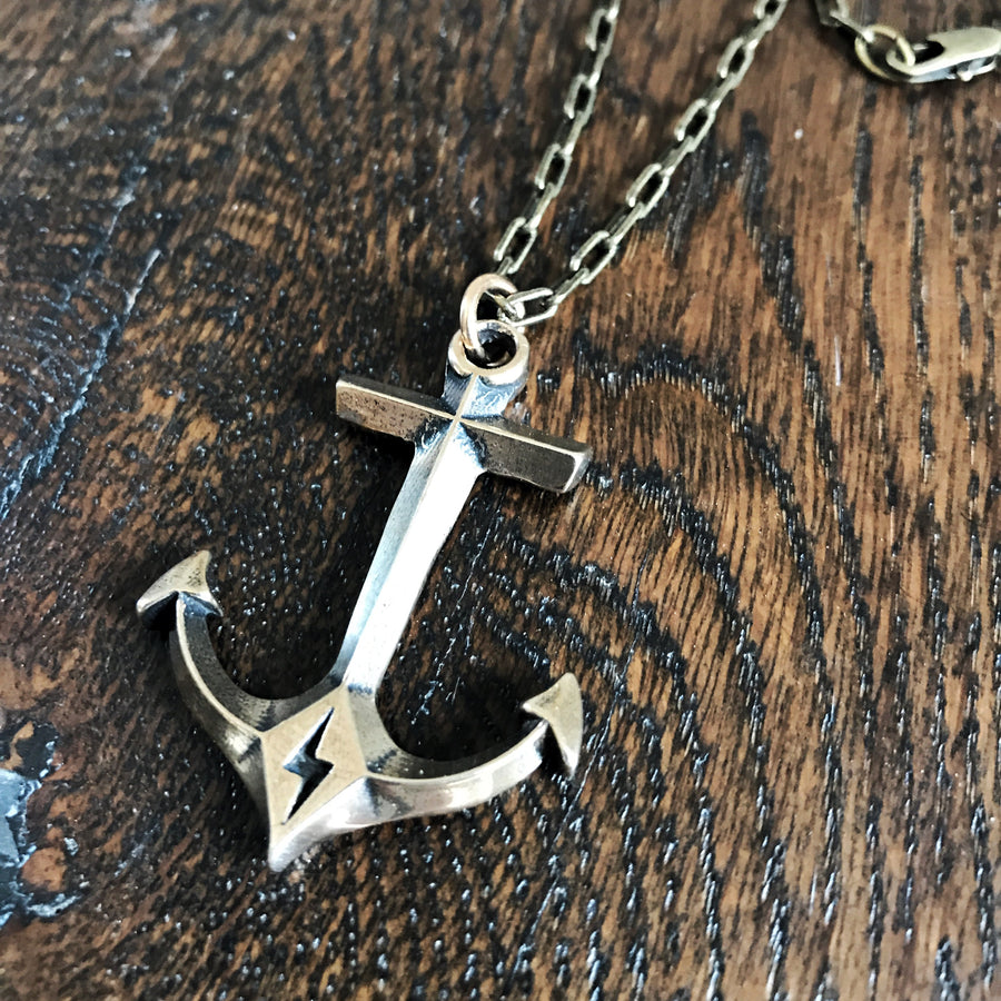 Hold Fast Anchor pendant on cable chain against dark wood