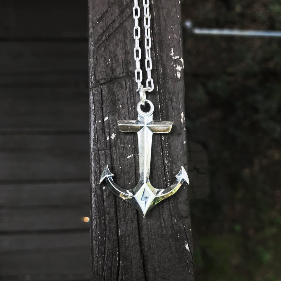 Anchor pendant and cable chain hanging against wood