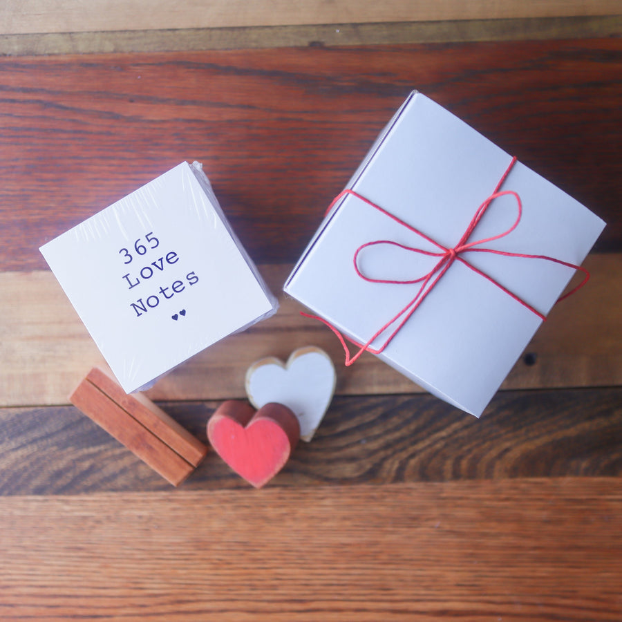 Gift-boxed 365 Love Notes set beside wooden hearts.