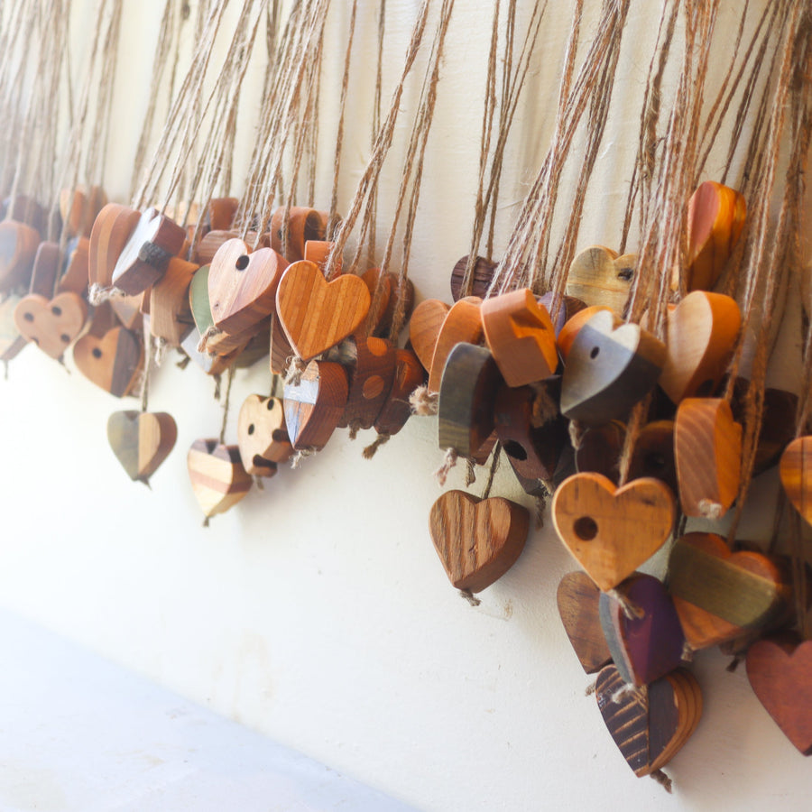 Collection of wooden heart charms hanging from long twine loops.