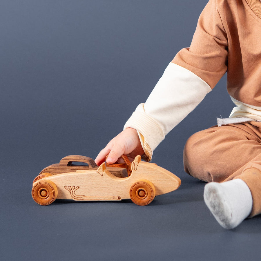 Child playing with a wooden toy car on the floor