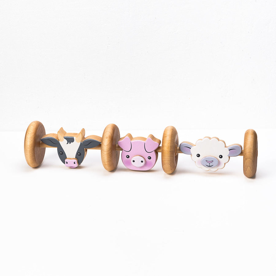 Linked wooden farm animal rolling toy with cow, pig and sheep designs