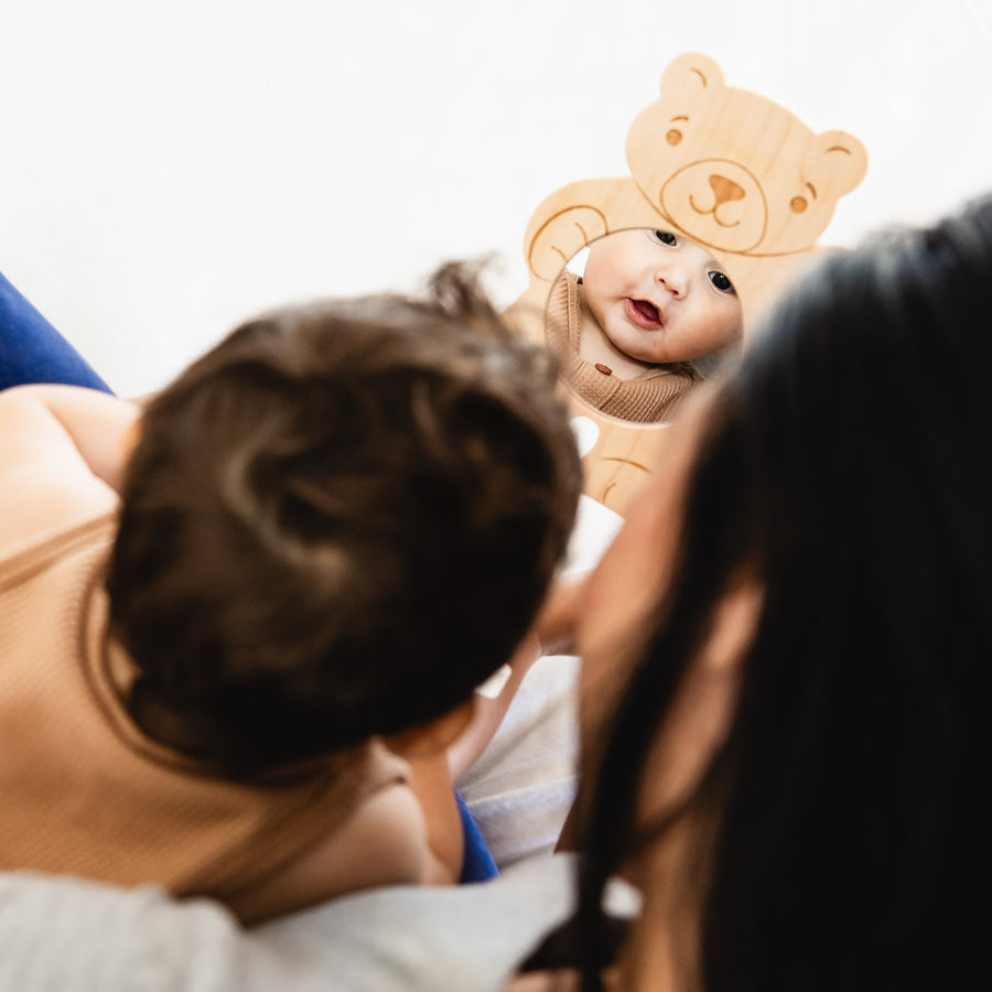 Child looking through a bear-shaped wooden discovery mirror