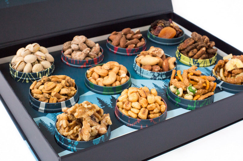 12 Days of Gourmet Nuts Winter Wonderland Selection with assorted nuts in festive tins, perfect for après ski treats by the fire.