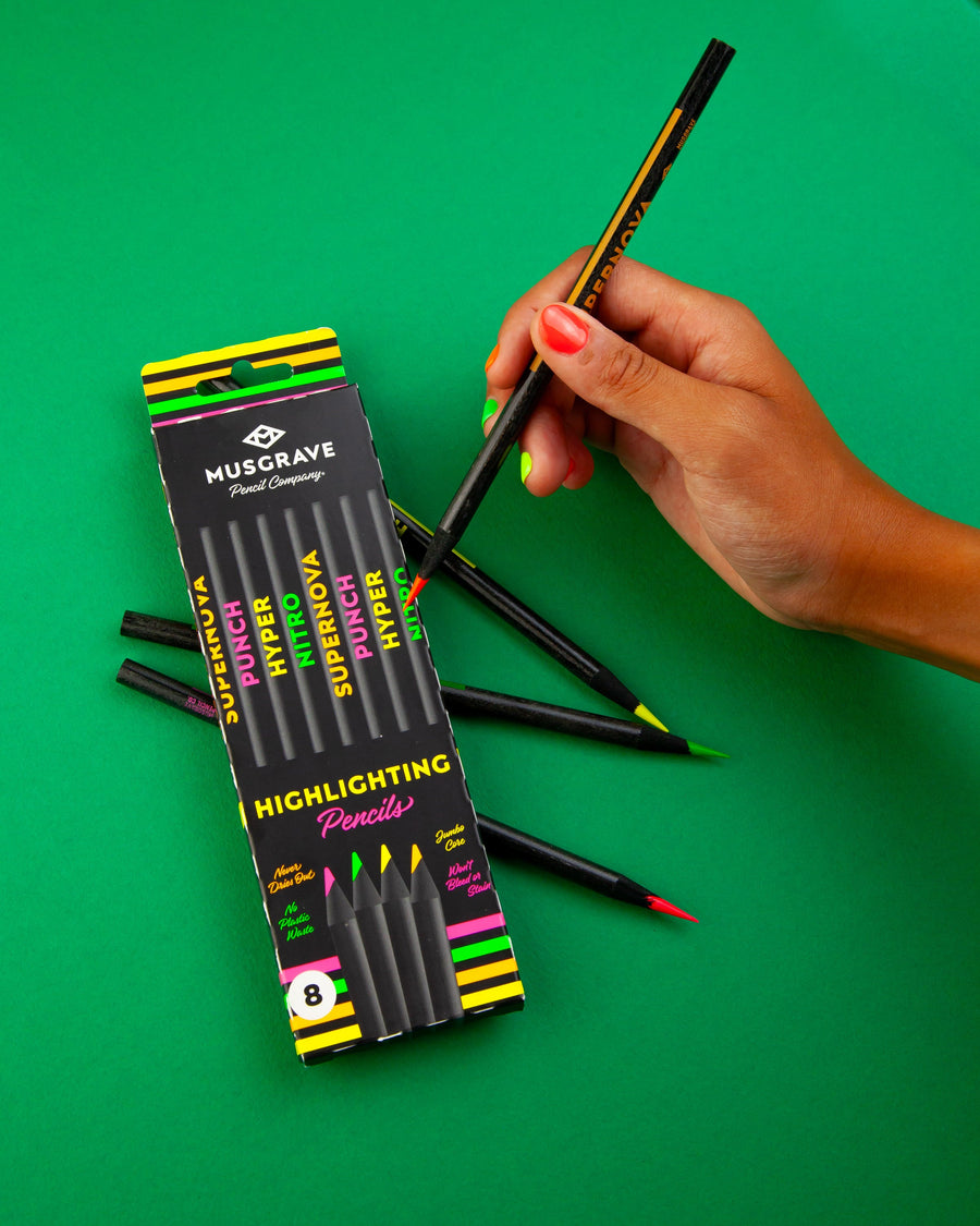 Hand holding a highlighter pencil beside the box on green