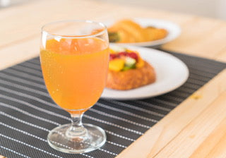 Prepared orange drink with a meal in the background, serving suggestion
