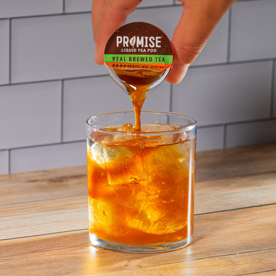 Hand pouring Mango Black tea concentrate over ice