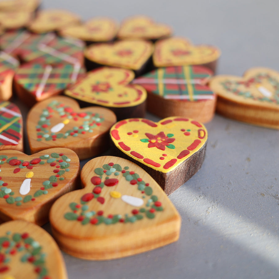 Hand-painted wooden hearts with colorful Christmas patterns.