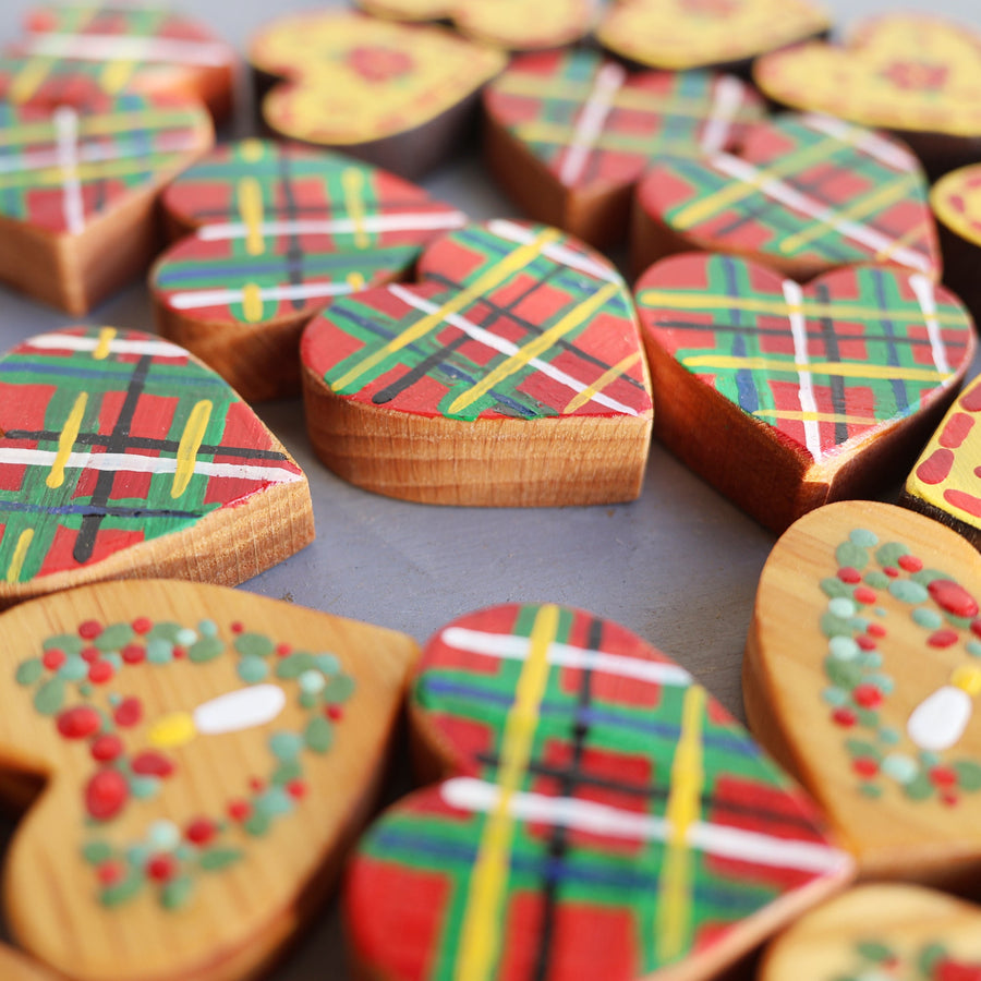 Hand-painted wooden hearts with colorful Christmas patterns.
