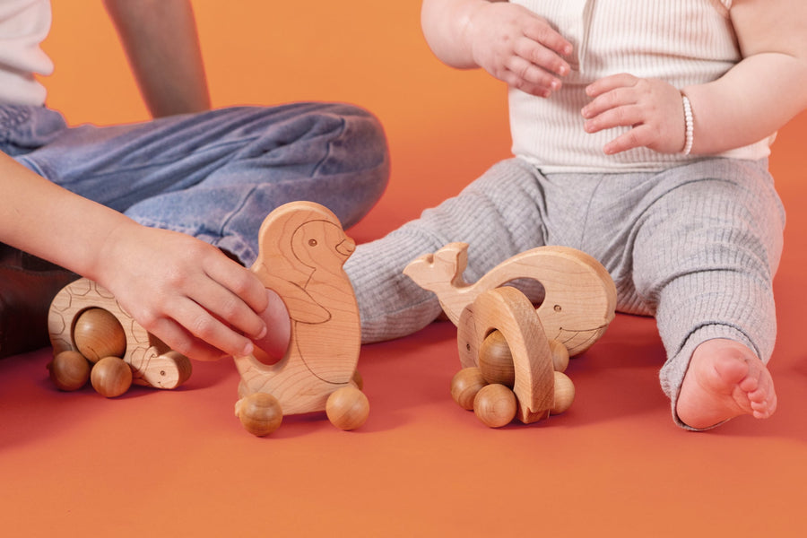 Children exploring wooden animal push toys with spherical wheels