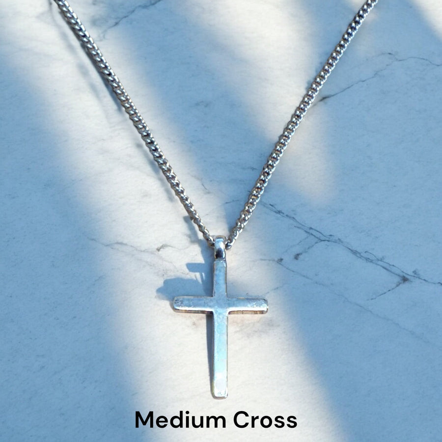 Medium Classic Cross pendant on chain against pale stone