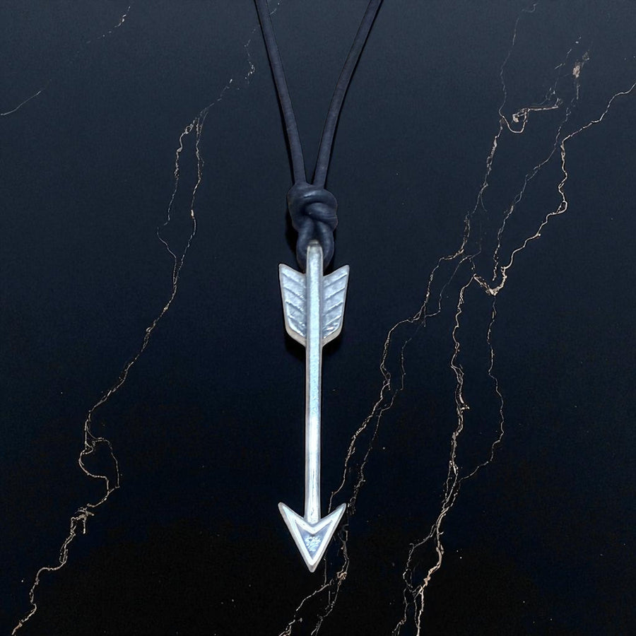 Arrow necklace on black cord against a dark background