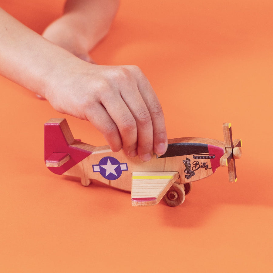 Child’s hands holding and guiding a wooden toy airplane