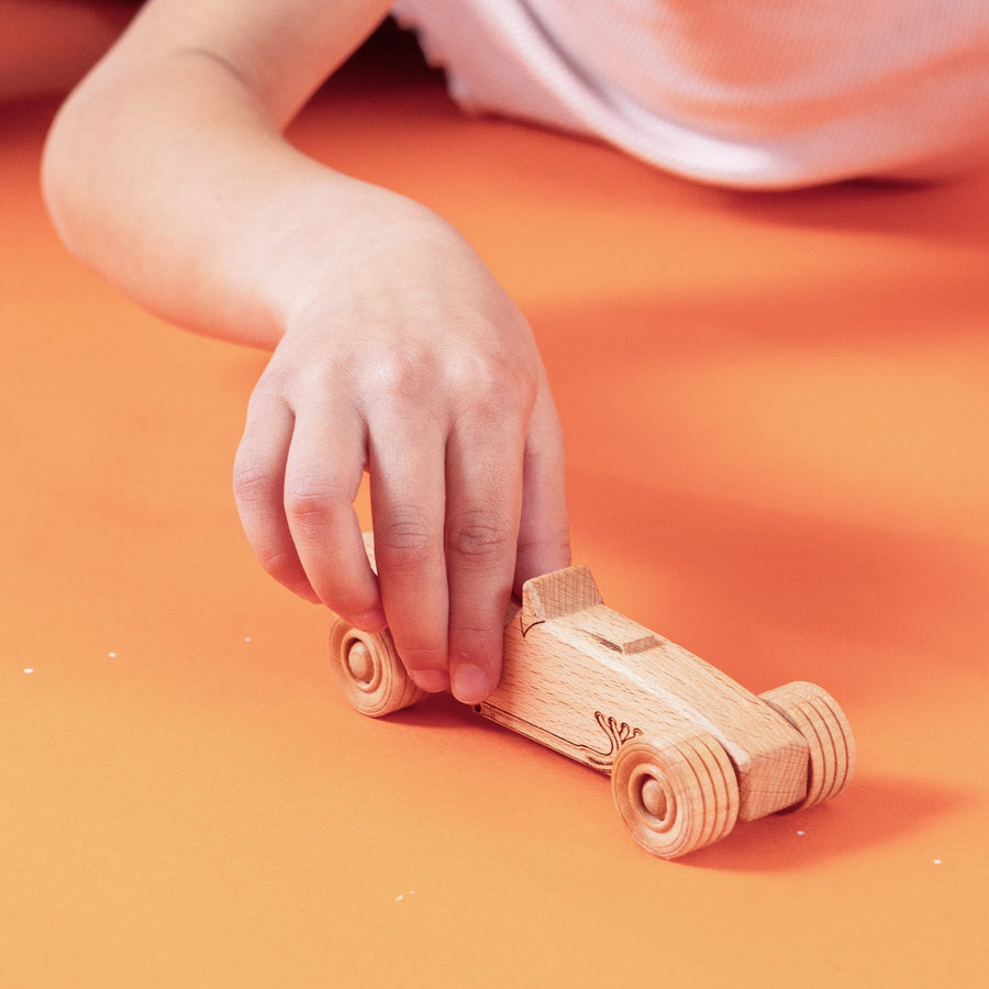 Child’s hands pushing a wooden toy car on a tabletop