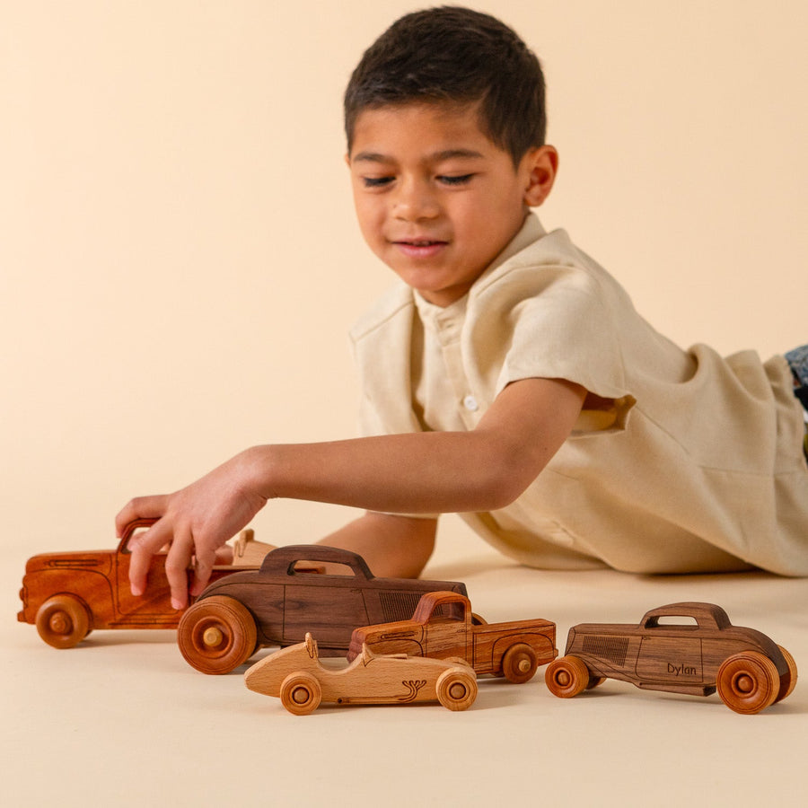Child arranging an assortment of wooden toy cars